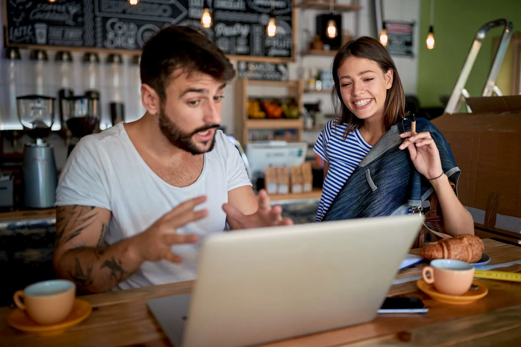 Excited business owner looking at his computer with his wife beside him smiling